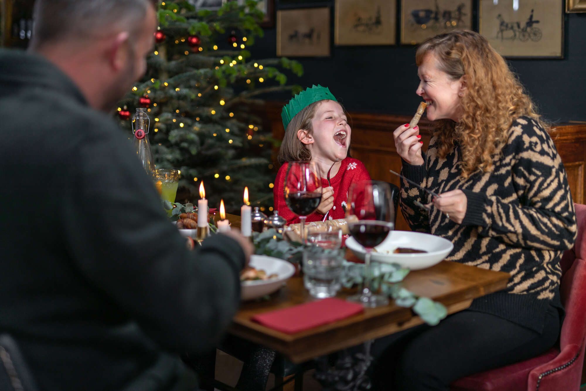 Family by the Christmas tree enjoying their Christmas Day lunch